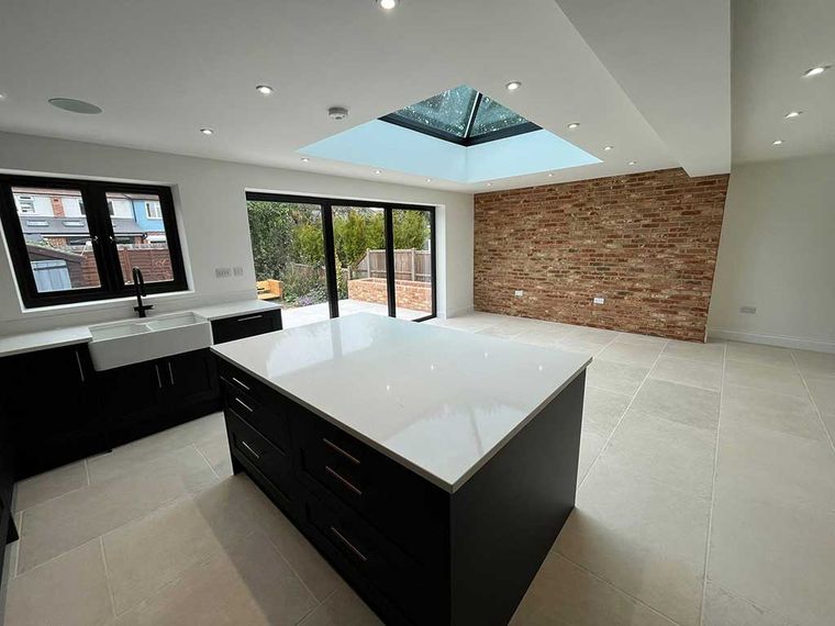 Open plan kitchen extension with an island, lantern roof and exposed brick wall