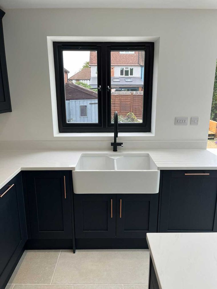 Navy shaker kitchen with a butler sink below the window