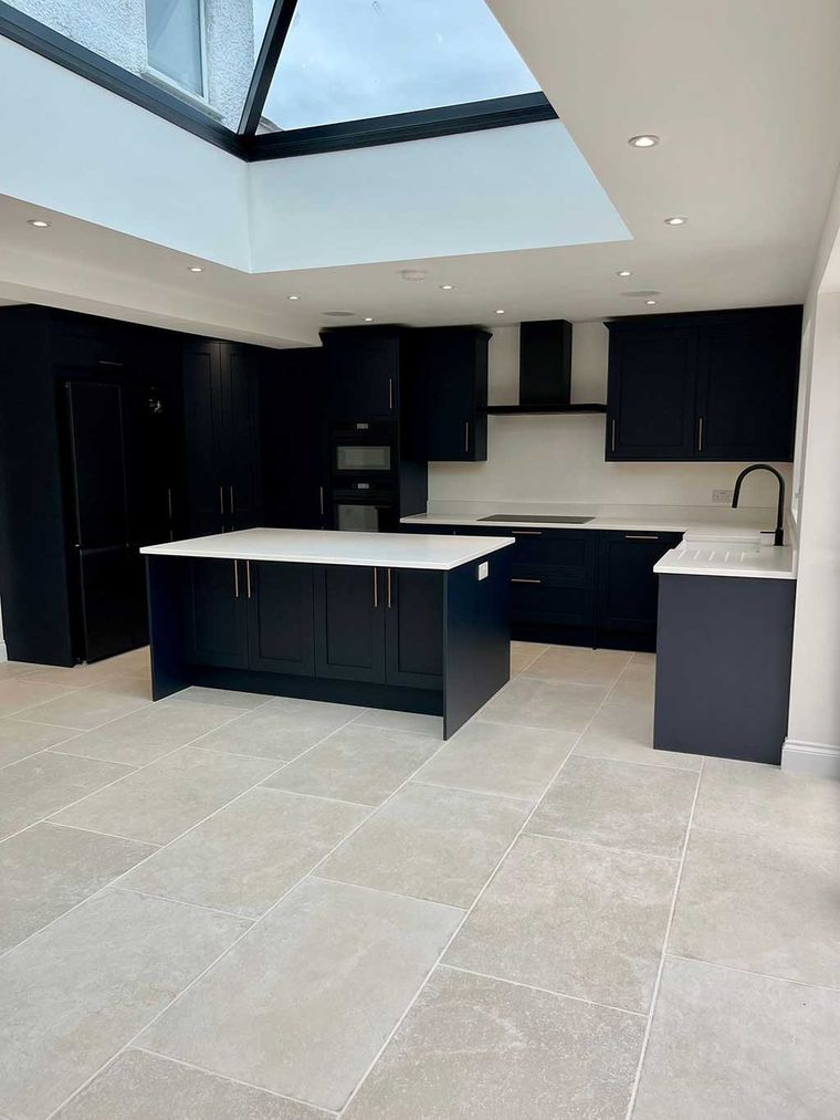 Open plan navy kitchen with a roof lantern and tiled floor