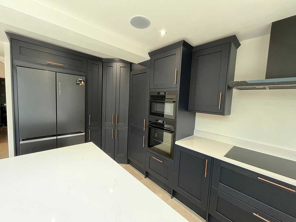 Navy kitchen units with built in ovens and an American style fridge