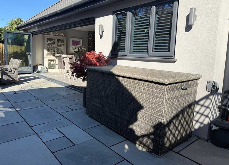 Bifold doors and shuttered windows onto a grey paved patio