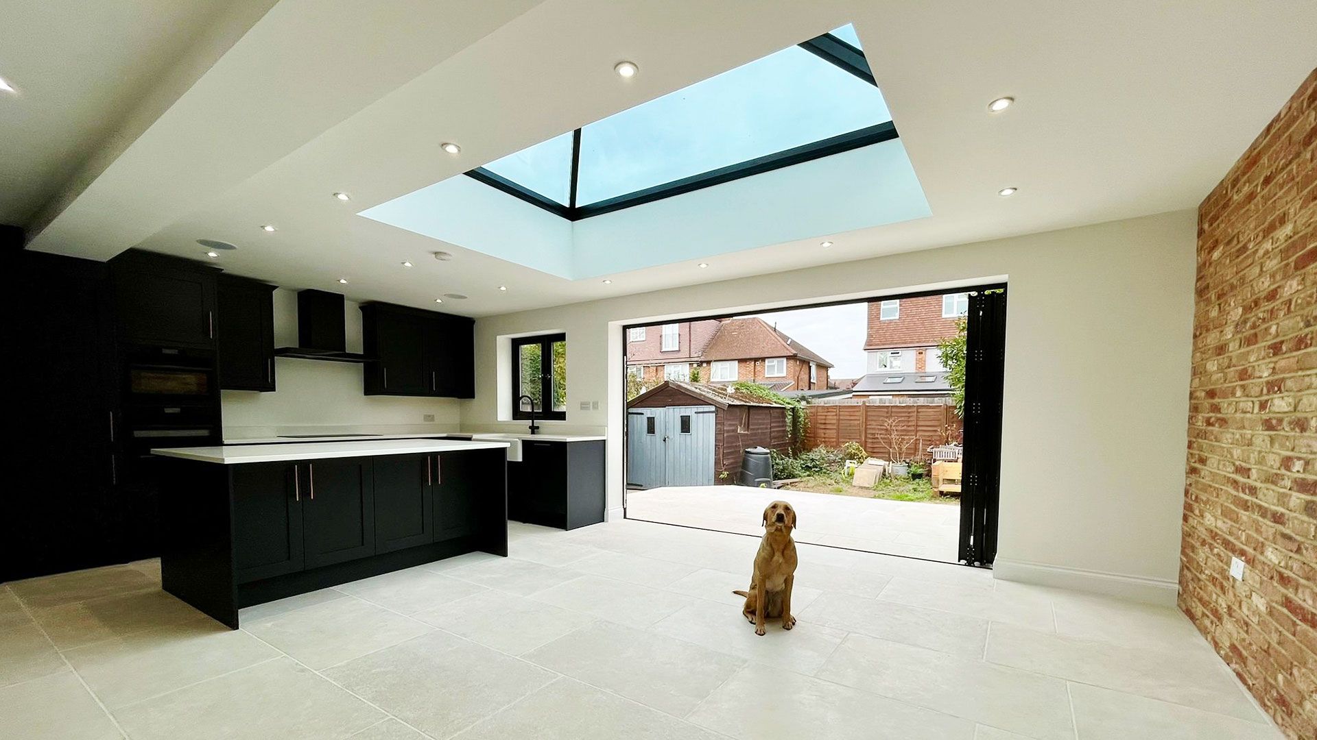 Kitchen extension with a roof lantern, exposed brick wall and bifold doors open to the garden